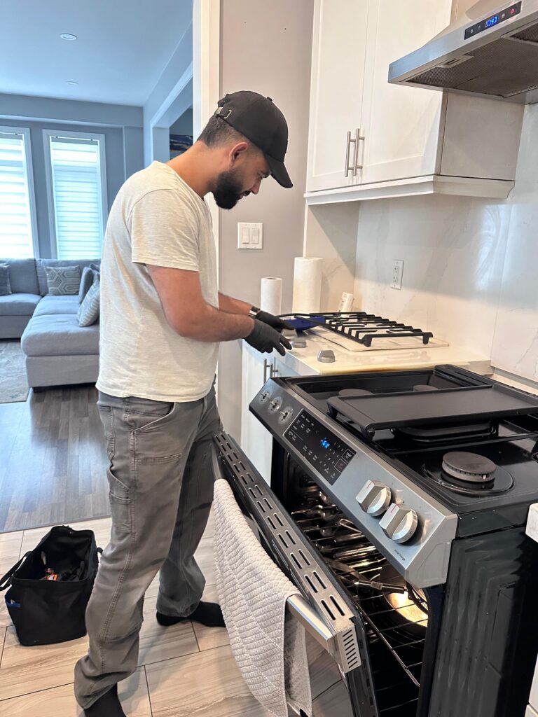 Appliance repair technician servicing a residential oven in Brampton